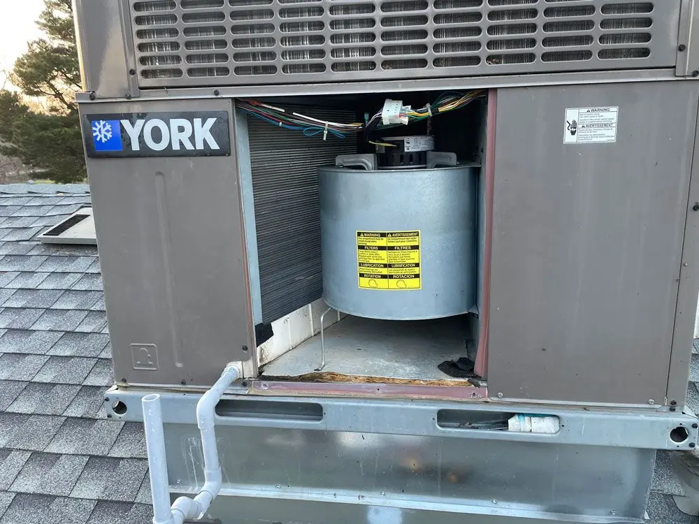 Rooftop York packaged HVAC unit opened for service, showing the blower wheel and wiring inside
