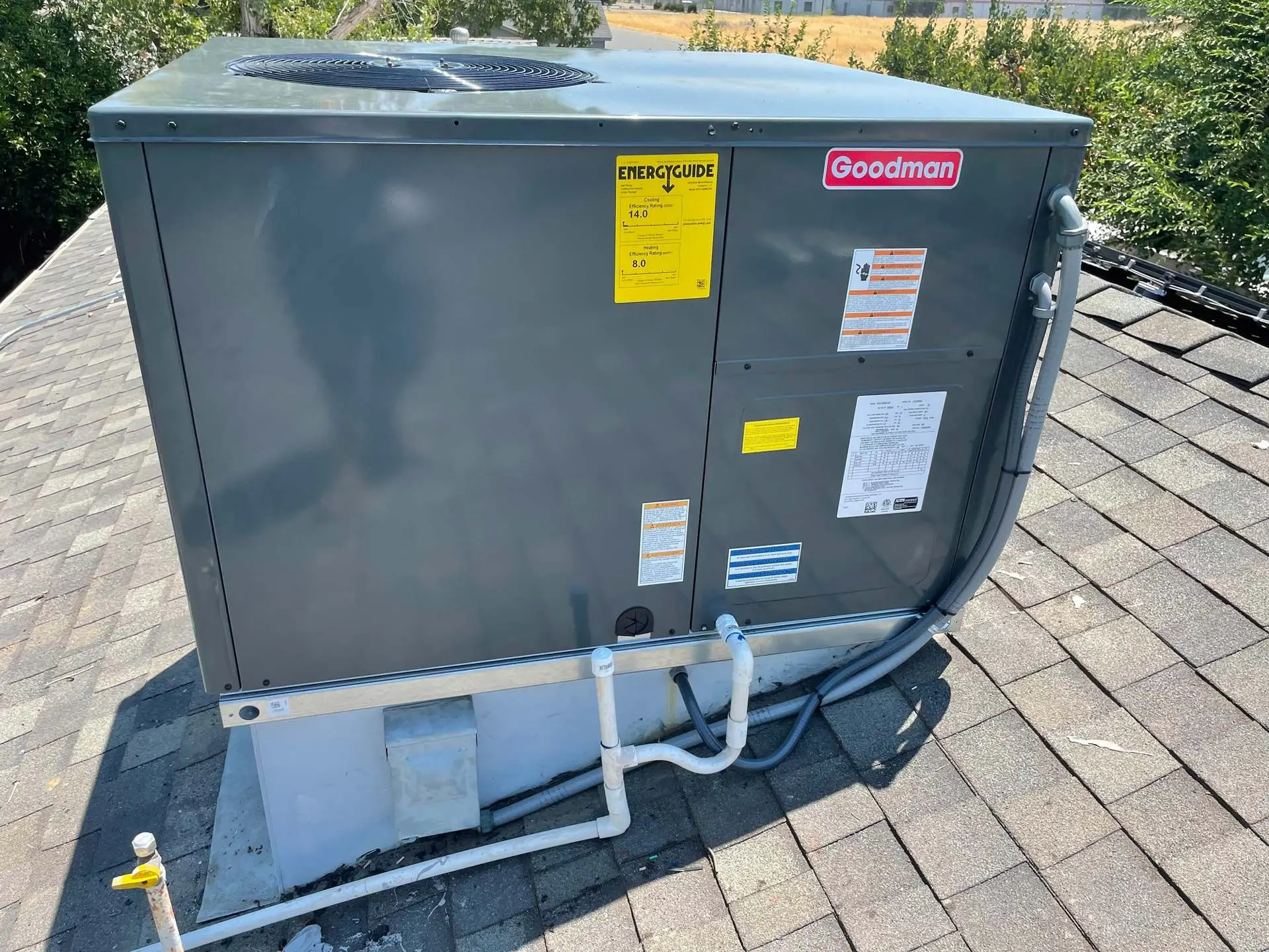 Goodman rooftop packaged heating and cooling unit installed on a shingled residential roof